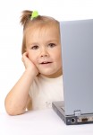 Cute little girl is looking out from her laptop